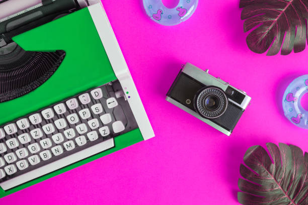 istock Flat lay of typewriter with retro camera and inflatable floats with monstera leaves abstract on rose. 1126058430