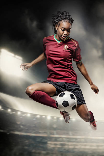 Female Football Player in action in a stadium African Female Football Player controlling a Soccer Ball in front of Stadium Lights womens soccer stock pictures, royalty-free photos & images