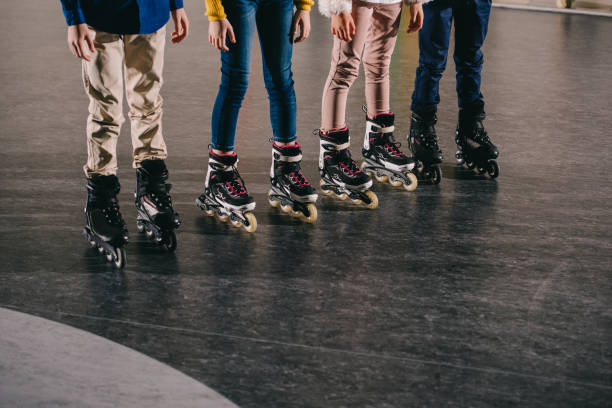 Partial view of children legs in roller skates standing in roller rink Partial view of children legs in roller skates standing in roller rink roller rink stock pictures, royalty-free photos & images