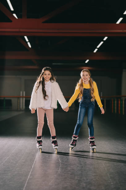istock Two cute long haired children in roller skates standing in roller rink and holding hands 1126058498