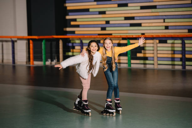 Happy smiling children skating together with raised hands Happy smiling children skating together with raised hands roller rink stock pictures, royalty-free photos & images