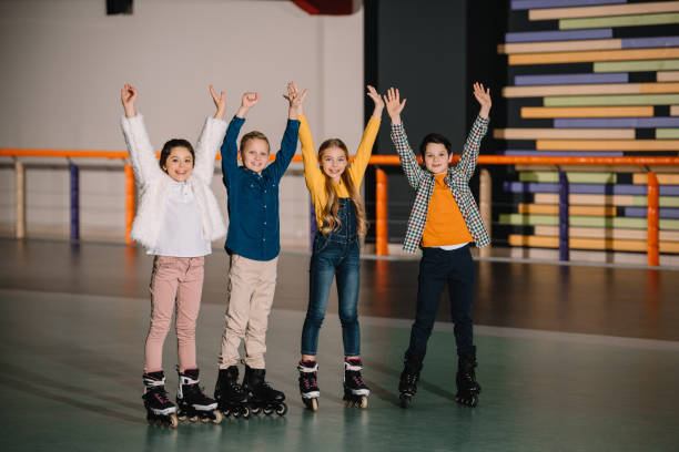 istock Happy smiling children in roller skates standing in spacious roller rink with hands up 1126058540