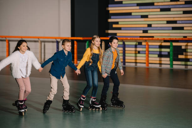 istock Group of smiling children skating in roller rink with holding hands 1126058544