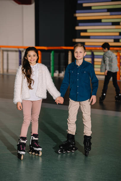 istock Two beautiful smiling children in roller skates standing with holding hands 1126058552