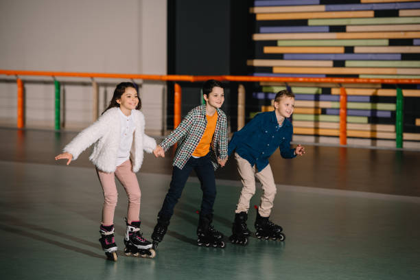 istock Three happy smiling children skating in roller rink with holding hands 1126058560