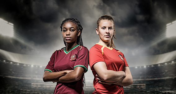 Two mixed race Female Football Players posing in front of Stadium Lights