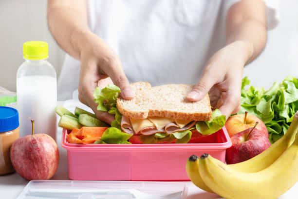 mère prépare school lunch box set, sandwich au fromage jambon avec concombre, carottes et noix, fruits et légumes en boîte. aliments sains et alimentation. - lunch packed lunch lunch box apple photos et images de collection