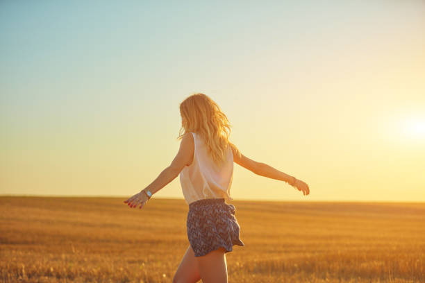 Picture of gorgeous young woman standing in the field. Looking aside.