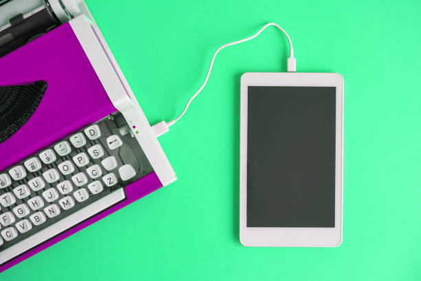 istock High angle view of vintage typewriter connected with digital tablet on green. 1126059020