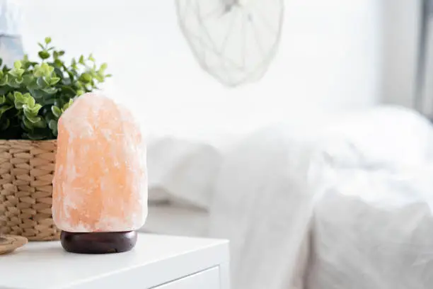 Photo of Himalayan pink salt crystals lamp on the table in bedroom, therapy healthy.