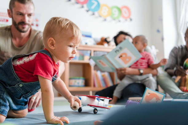 kleiner junge spielt in einem klassenzimmer - adult activity child father stock-fotos und bilder