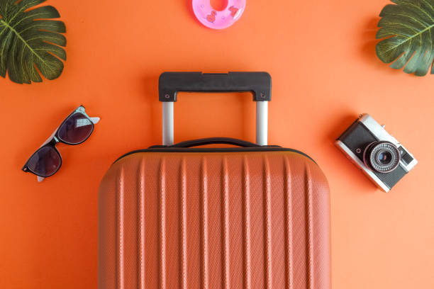 istock Luggage with summer vacation accessories on orange. 1126060612