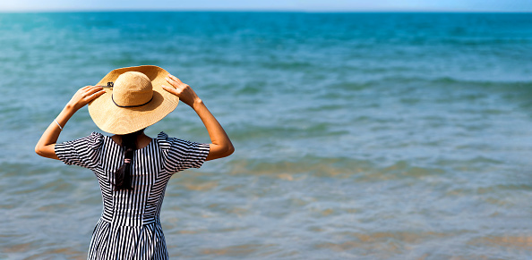 Happy woman by the seaside wearing red dress with copy space