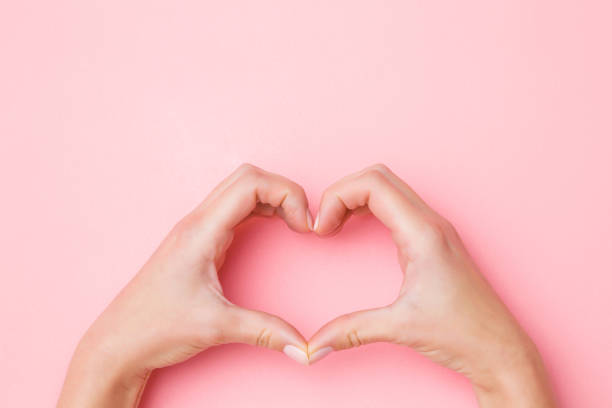 istock Heart shape created from young woman's hands on pastel pink background. Love and happiness concept. Empty place for emotional, sentimental text, quote or sayings. Closeup. 1126062229