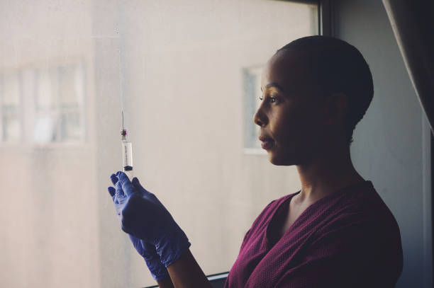 Portrait of a female nurse testing a syringe in the hospital side view toned stock photo