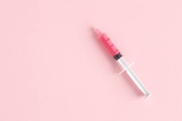 istock Syringe with rose liquid on pastel background abstract. 1126063221