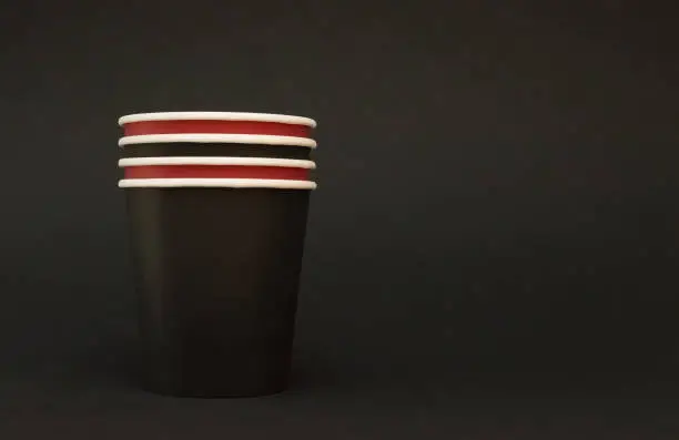 a stack of paper black and red coffee glasses stand on a black background