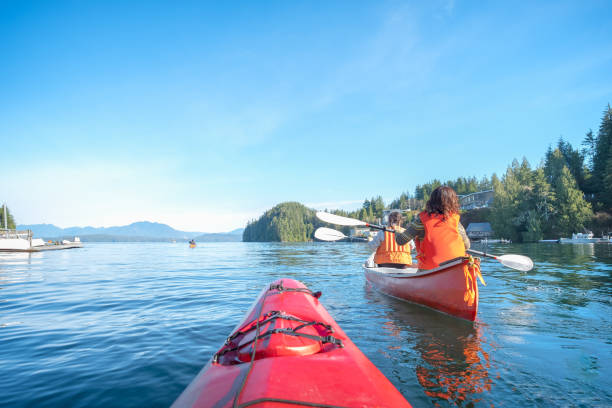 Personal Perspective of Ocean Kayaker Following Multi-Ethnic Family in Canoe Mature mother and teen daughter enjoy morning kayaking and canoeing in rural Bamfield, British Columbia, Canada. british columbia photos stock pictures, royalty-free photos & images