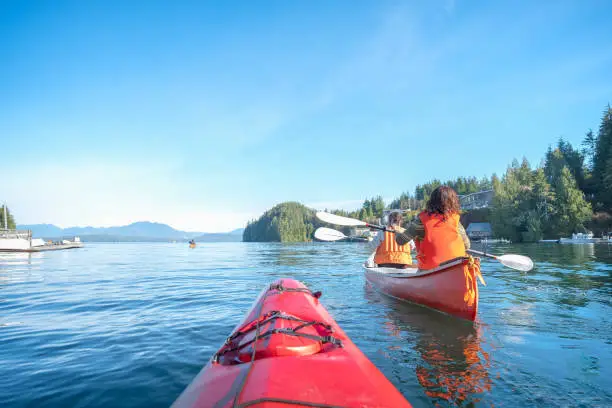 Photo of Personal Perspective of Ocean Kayaker Following Multi-Ethnic Family in Canoe