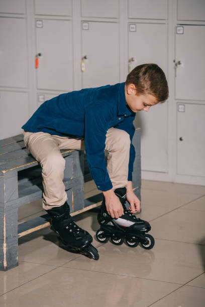 istock Kid in blue shirt putting on black roller skates 1126066130