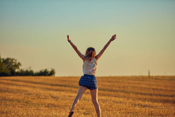 Cute young woman jumping in a wheat field.