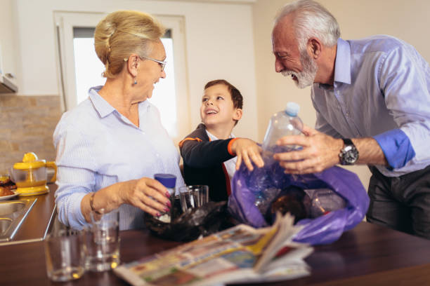 Boy with grandparents separating recyclable trash at home