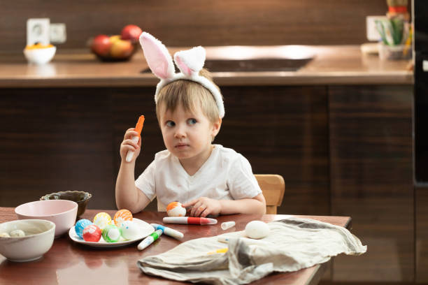 istock Cute little toddler boy wearing Easter bunny ears paints Easter eggs. 1126071045