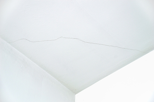 Old cracked plaster wall surface for background or texture in the corner of a ceiling