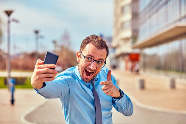 istock Funny businessman with thumbs up while using smartphone outdoors. 1126074327