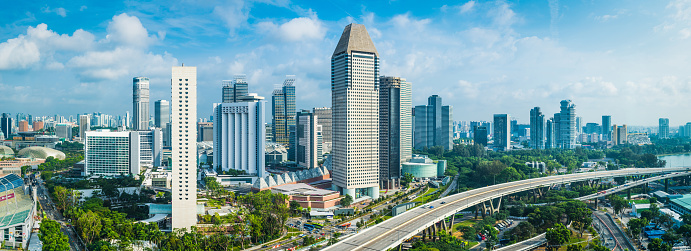 Aerial panorama over the towering skyscrapers and busy highways of downtown Singapore surrounding Marina Bay.