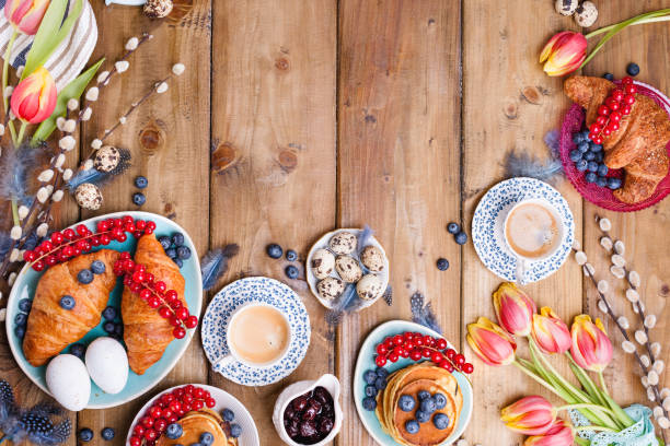 istock Easter breakfast flat lay with fresh coffee, berries and pastries , orange tulips, croissants with bacon and various sweets , colored quail eggs and spring holidays decorations. Top view. Copy space. 1126076147