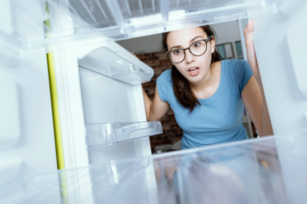 istock Young hungry desperate woman looking into her empty fridge, she is panicking 1126077369