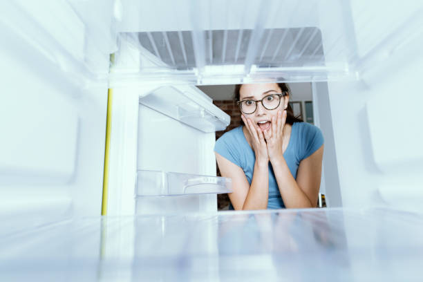 istock Young hungry desperate woman looking into her empty fridge, she is panicking 1126077376