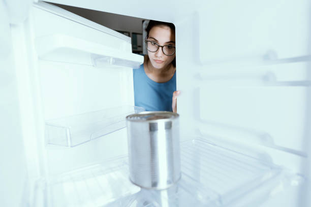 istock Sad woman looking into her empty fridge with no groceries 1126077388