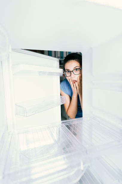 istock Young hungry desperate woman looking into her empty fridge, she is panicking 1126077392