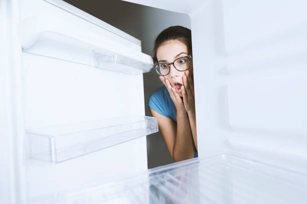istock Young hungry desperate woman looking into her empty fridge, she is panicking 1126077399