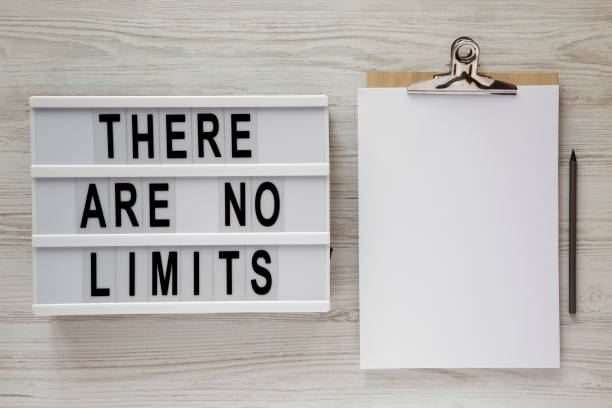 istock Lightbox with text 'There are no limits', clipboard with sheet of paper and pencil on a white wooden surface, top view. 1126078110