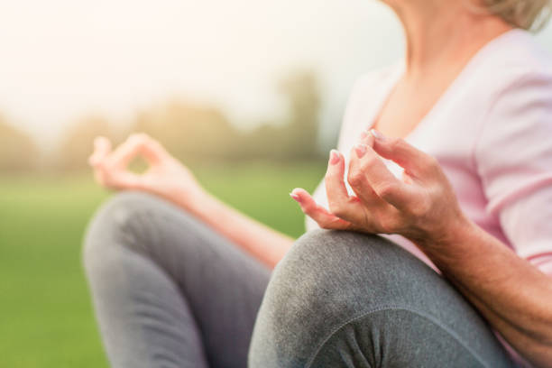Hands of mature woman practicing yoga