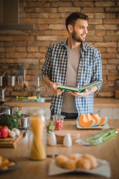 istock Smiling man following recipe from a cookbook in the kitchen. 1126088845