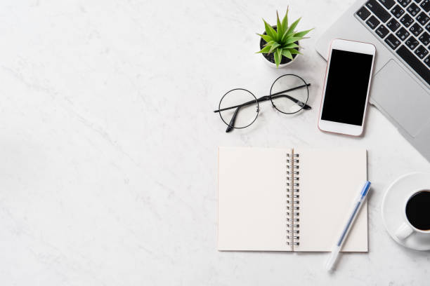 istock Stylized marble office working desk with smartphone, laptop, glasses and coffee, workspace design, mock up, topview, flatlay, copyspace, closeup 1126090427