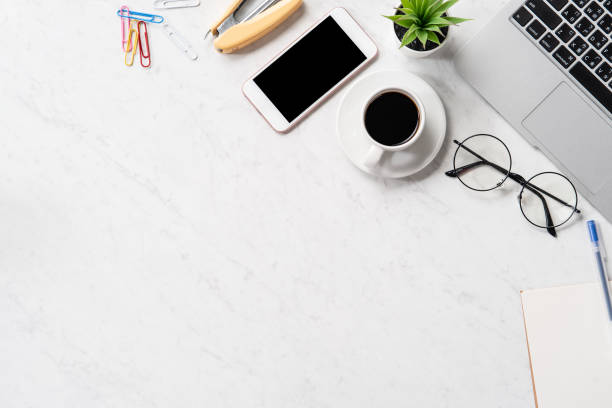 istock Stylized marble office working desk with smartphone, laptop, glasses and coffee, workspace design, mock up, topview, flatlay, copyspace, closeup 1126090605