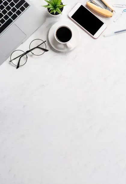 Stylized marble office working desk with smartphone, laptop, glasses and coffee, workspace design, mock up, topview, flatlay, copyspace, closeup