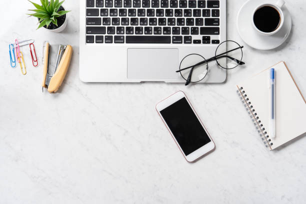 istock Stylized marble office working desk with smartphone, laptop, glasses and coffee, workspace design, mock up, topview, flatlay, copyspace, closeup 1126091057