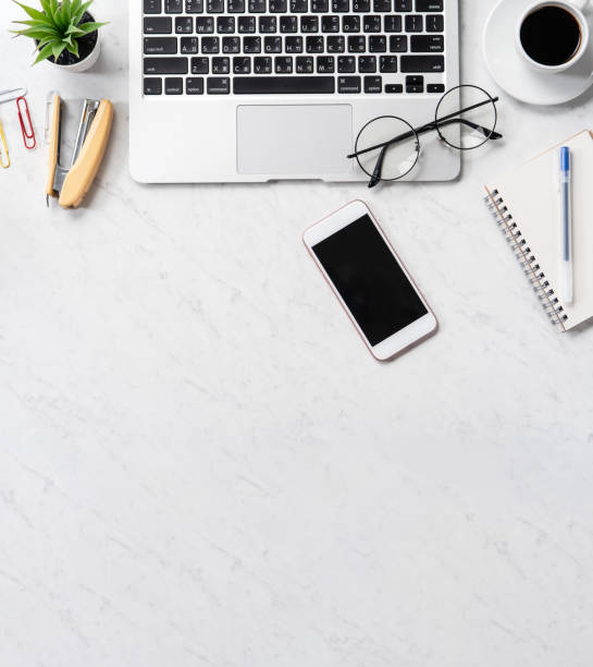 istock Stylized marble office working desk with smartphone, laptop, glasses and coffee, workspace design, mock up, topview, flatlay, copyspace, closeup 1126091335