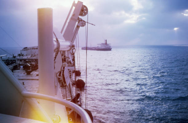 Vintage photo circa 1960s. Tanker ship in distance. Viewed from the deck of another ship. Natural light leaks and copy space. From a 35mm slide.