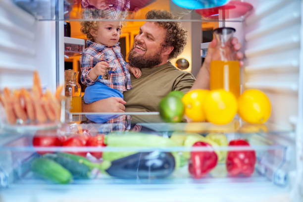 istock Father and son taking food from fridge late at night. 1126091891
