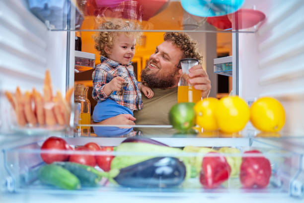 istock Father and son taking food from fridge late at night. 1126092616