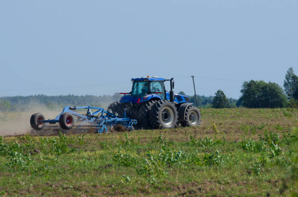 istock Blue tractor plowing the green field 1126093317