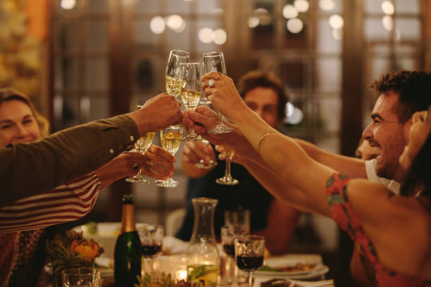 Group of people toasting drinks at a party. Young friends having drinks to celebrate a special occasion.