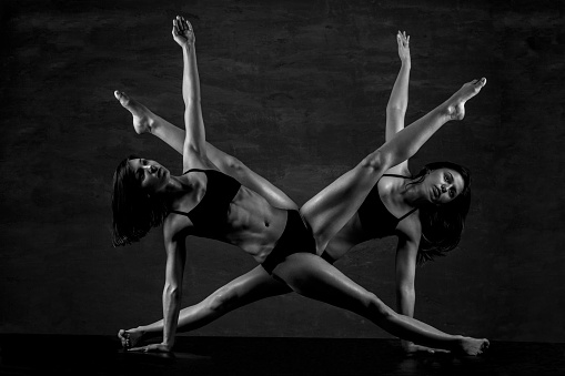 Two amazing young gymnastics woman practicing forms together in studio. Black and white series of photos with beautiful muscular young women